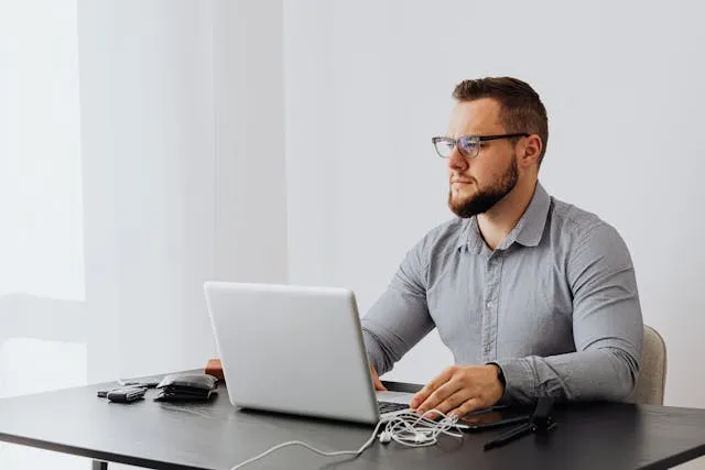 IT professional working on a laptop in an office environment representing a System Administrator.