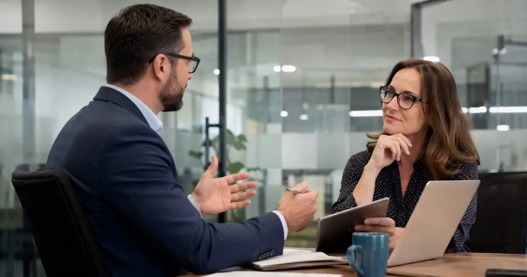 Recruiter discussing hiring needs with HR director in corporate office meeting